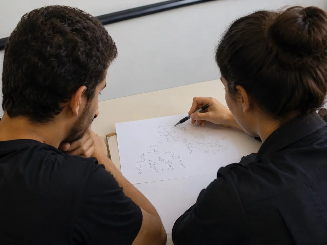 Duas pessoas relendo anotações num tablet apoiado numa mesa de madeira